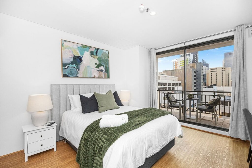 The master bedroom with a king bed, along with two bedside tables, two bedside lamps, a TV, and an ensuite bathroom.