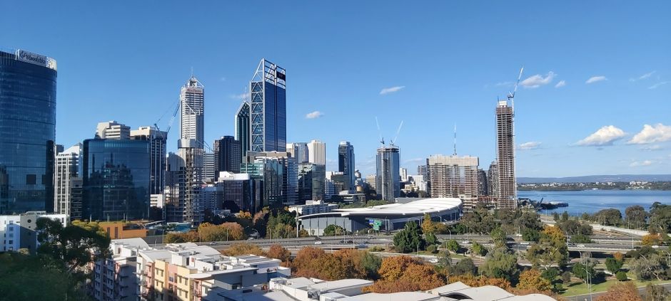 Perth CBD skyline with river, skyscrapers and surrounding parkland under blue sky
