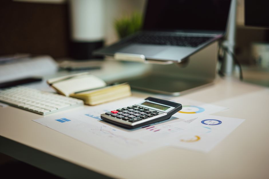 Desk workspace with laptop, calculator and financial documents for revenue analysis