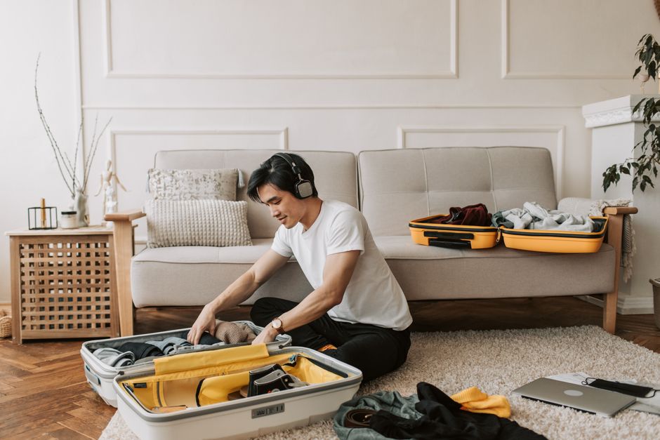Guest packing suitcase in living room, preparing for short-term rental stay