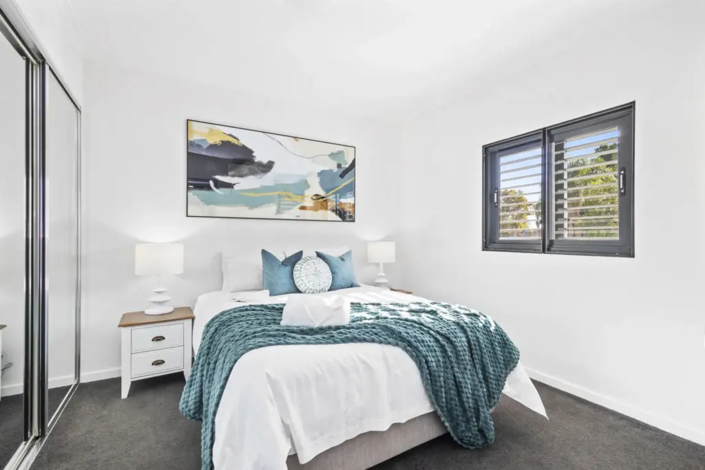 Bright bedroom with a queen bed, teal throw and abstract artwork in a Perth apartment